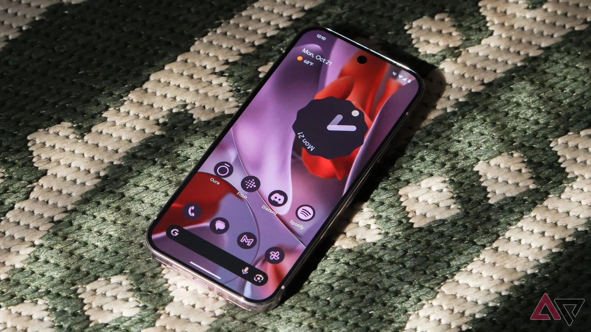 Điện thoại Google Pixel 9 Pro đặt trên thảm xanh với màn hình hiển thị giao diện Android 15