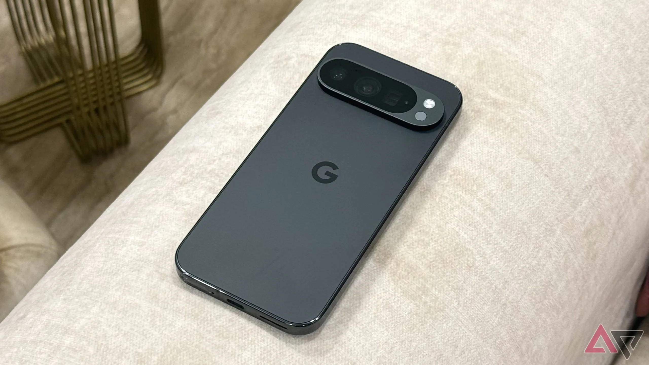 Điện thoại Google Pixel 9 Pro màu đen đặt trên ghế sofa.