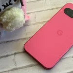 Điện thoại Google Pixel 9a màu Peony đặt cạnh đồ vật trang trí.
