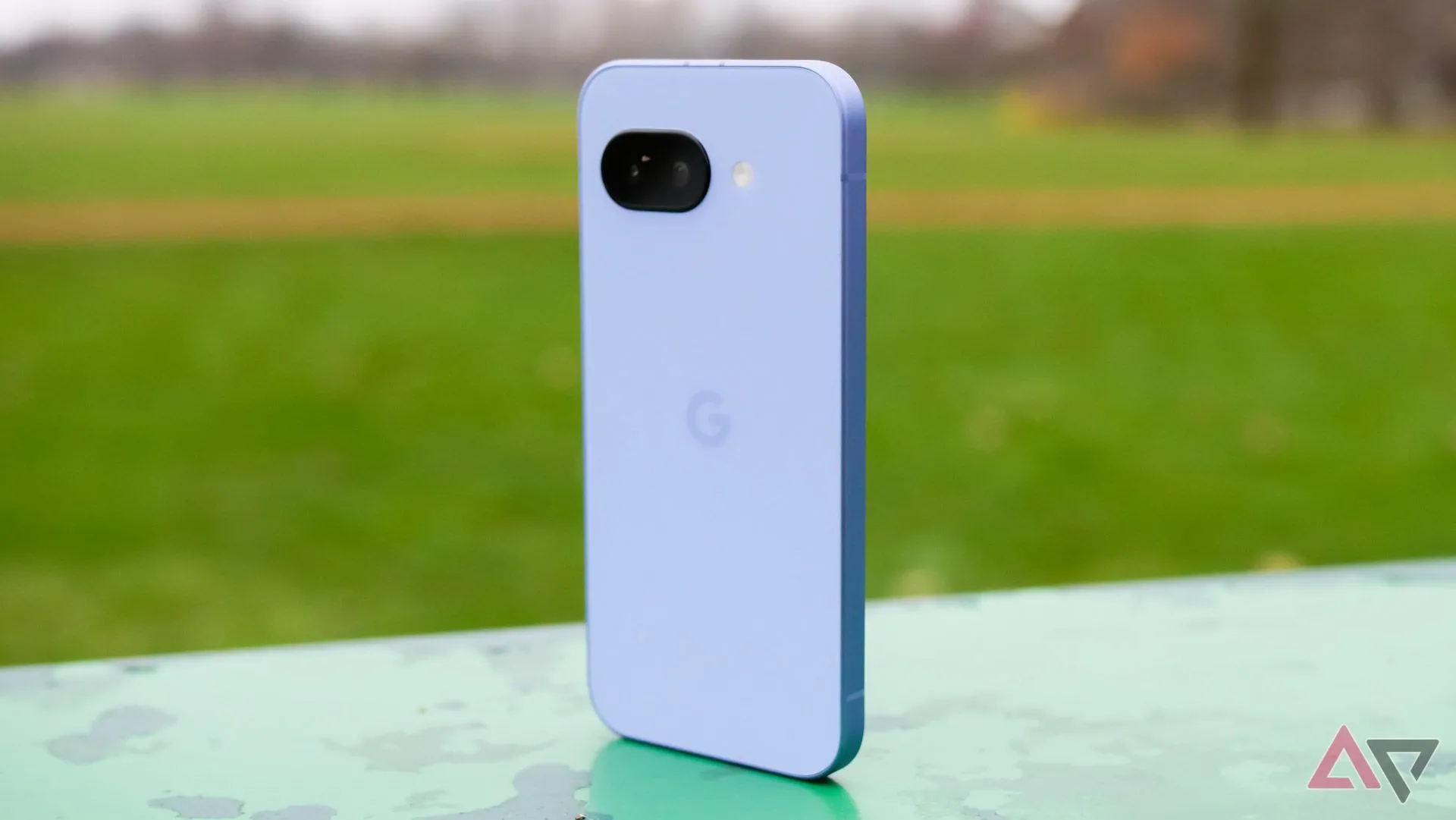 Google Pixel 9a màu tím đặt đứng trong công viên, khoe mặt lưng