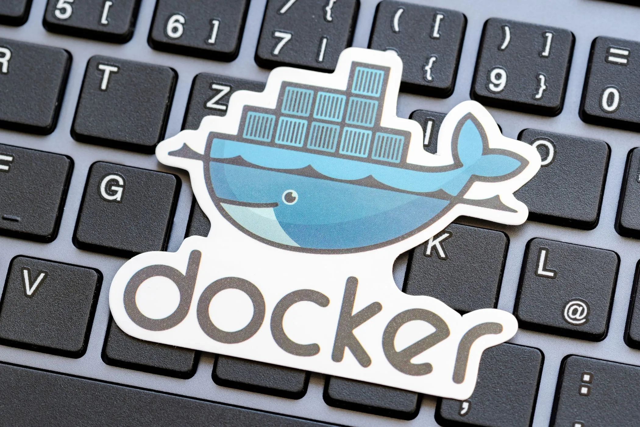 Logo Docker trên nền bàn phím laptop, biểu tượng của công cụ giúp đơn giản hóa việc tự host (self-hosting) dịch vụ.