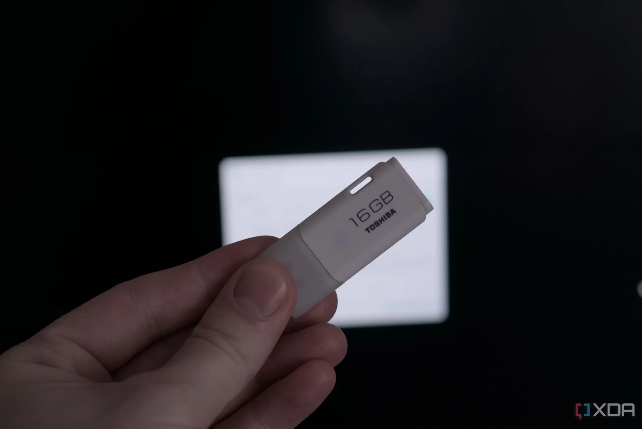 Bàn tay cầm một chiếc USB flash drive, minh họa nguy cơ từ thiết bị USB lạ độc hại
