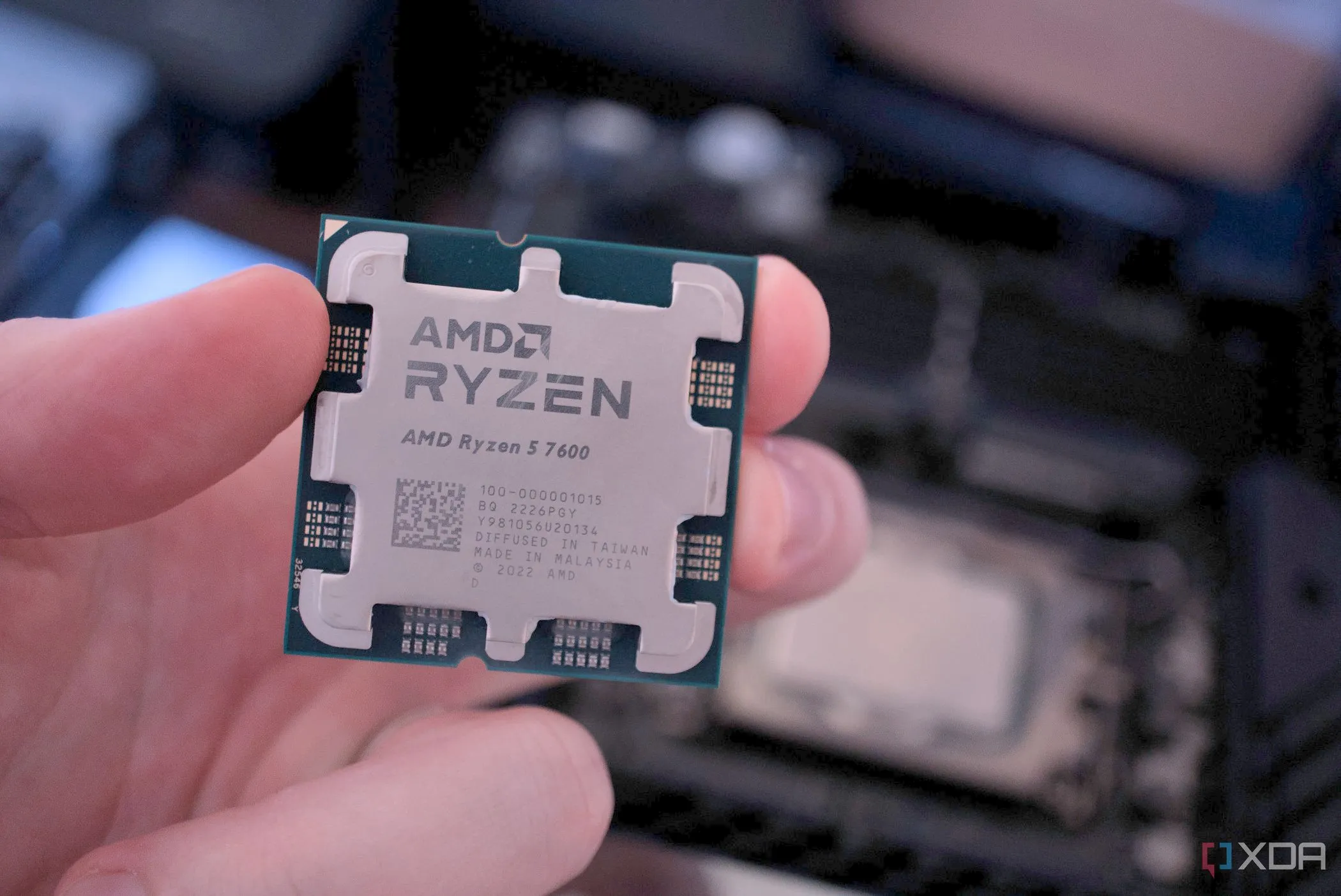 Bàn tay giữ bộ xử lý AMD Ryzen 7 7700 và CPU Intel