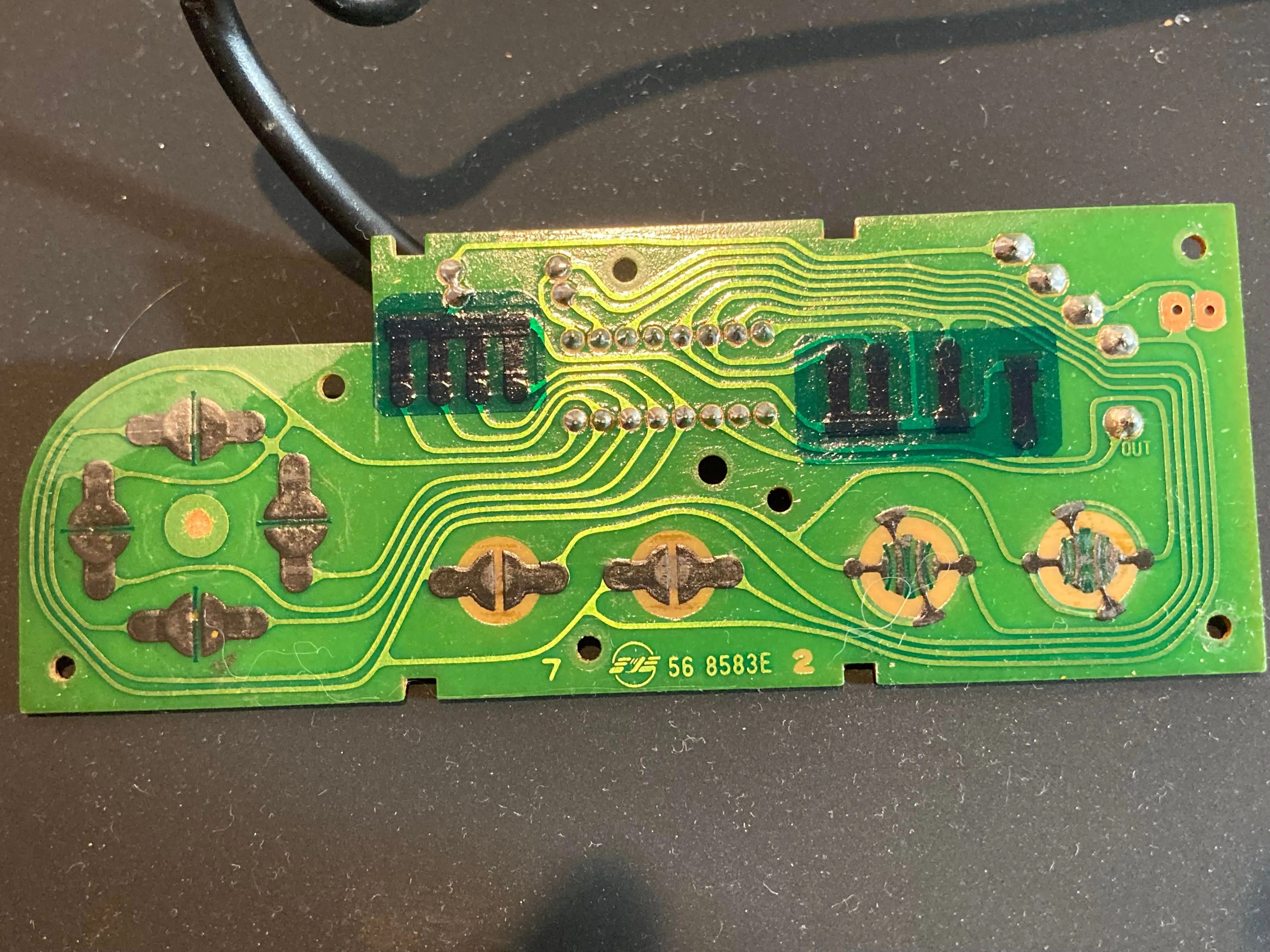 Bên trong tay cầm NES: Hình ảnh mặt trước bảng mạch in (PCB) với các tiếp điểm nút và chip shift register