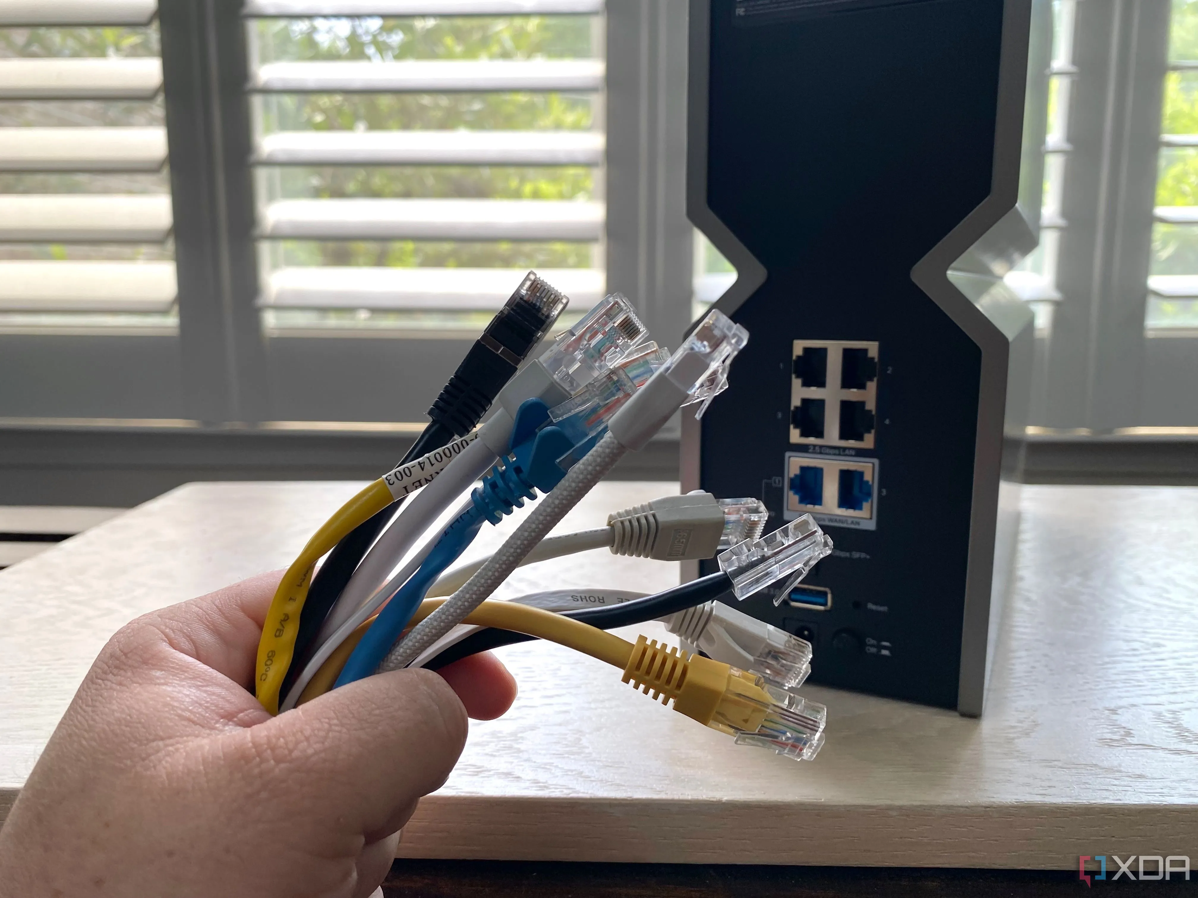 Bó cáp Ethernet đa dạng màu sắc đặt trước một bộ định tuyến (router), minh họa việc kết nối mạng có dây.