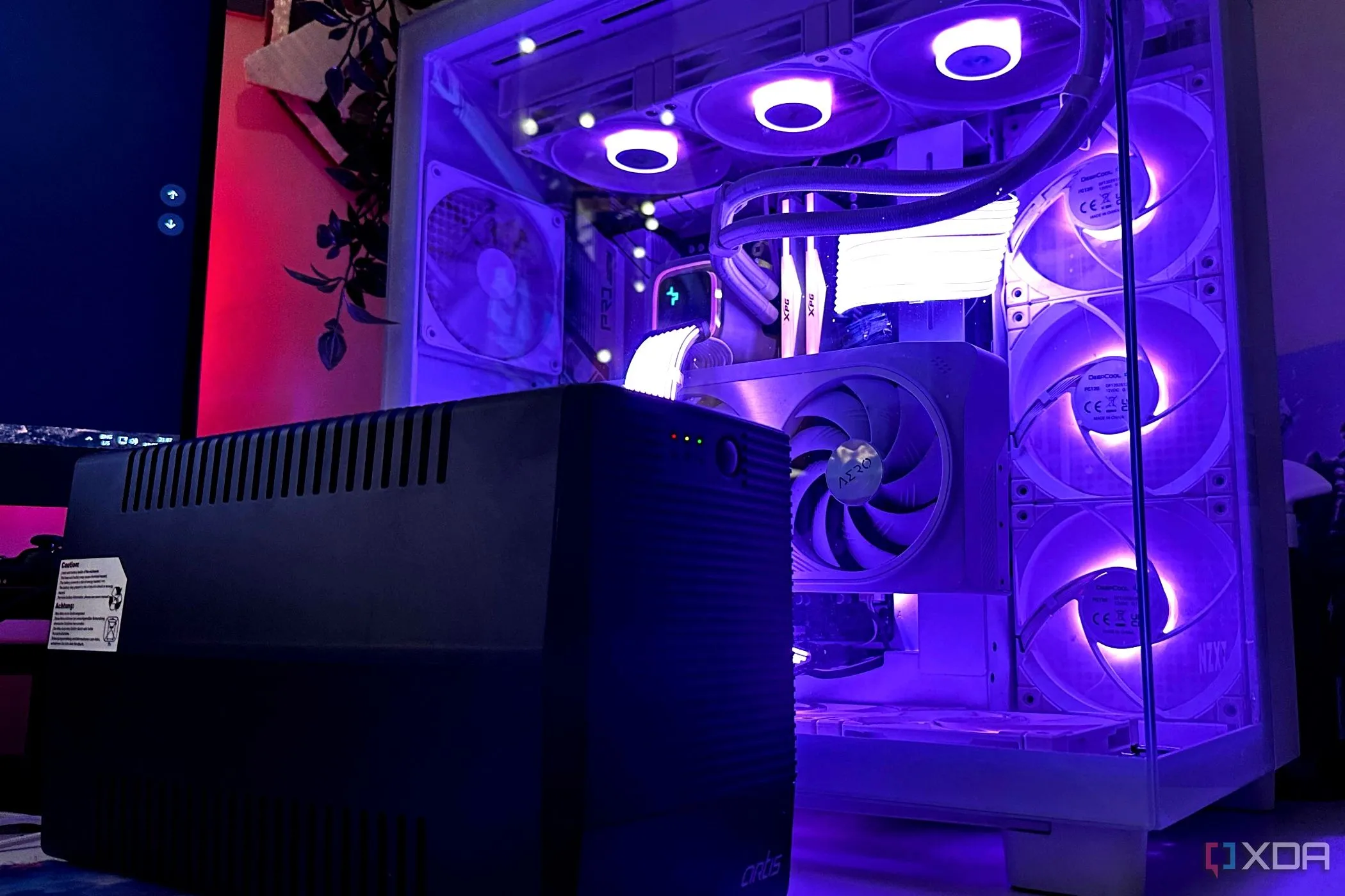 Bộ lưu điện (UPS) màu đen đặt cạnh thùng máy PC gaming, thiết bị thiết yếu để bảo vệ phần cứng khỏi sự cố điện.
