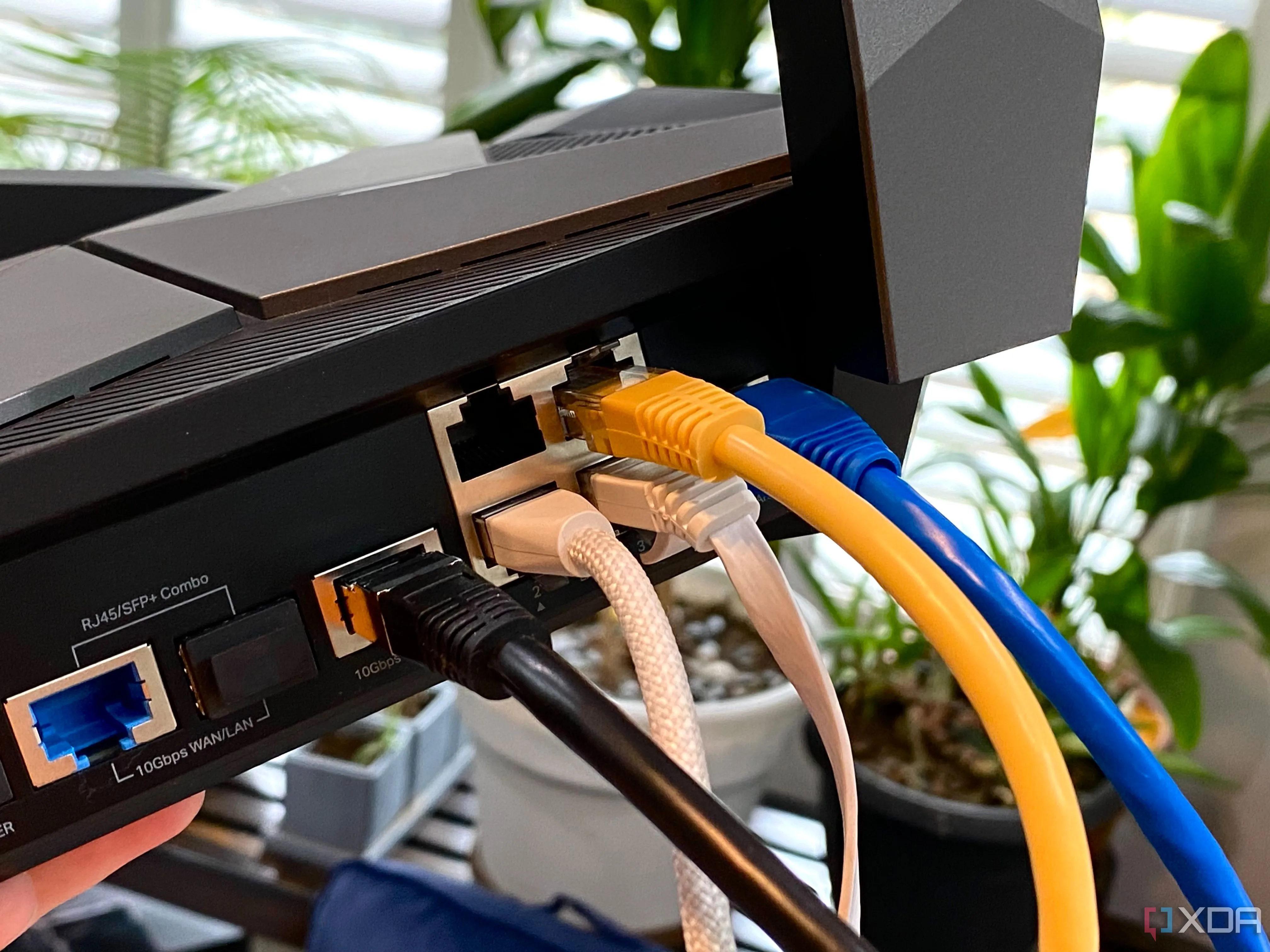 Các loại cáp Ethernet kết nối với router TP-Link Archer AXE300, biểu trưng cho sự kết nối vật lý mà ZeroTier biến đổi thành mạng LAN ảo toàn cầu