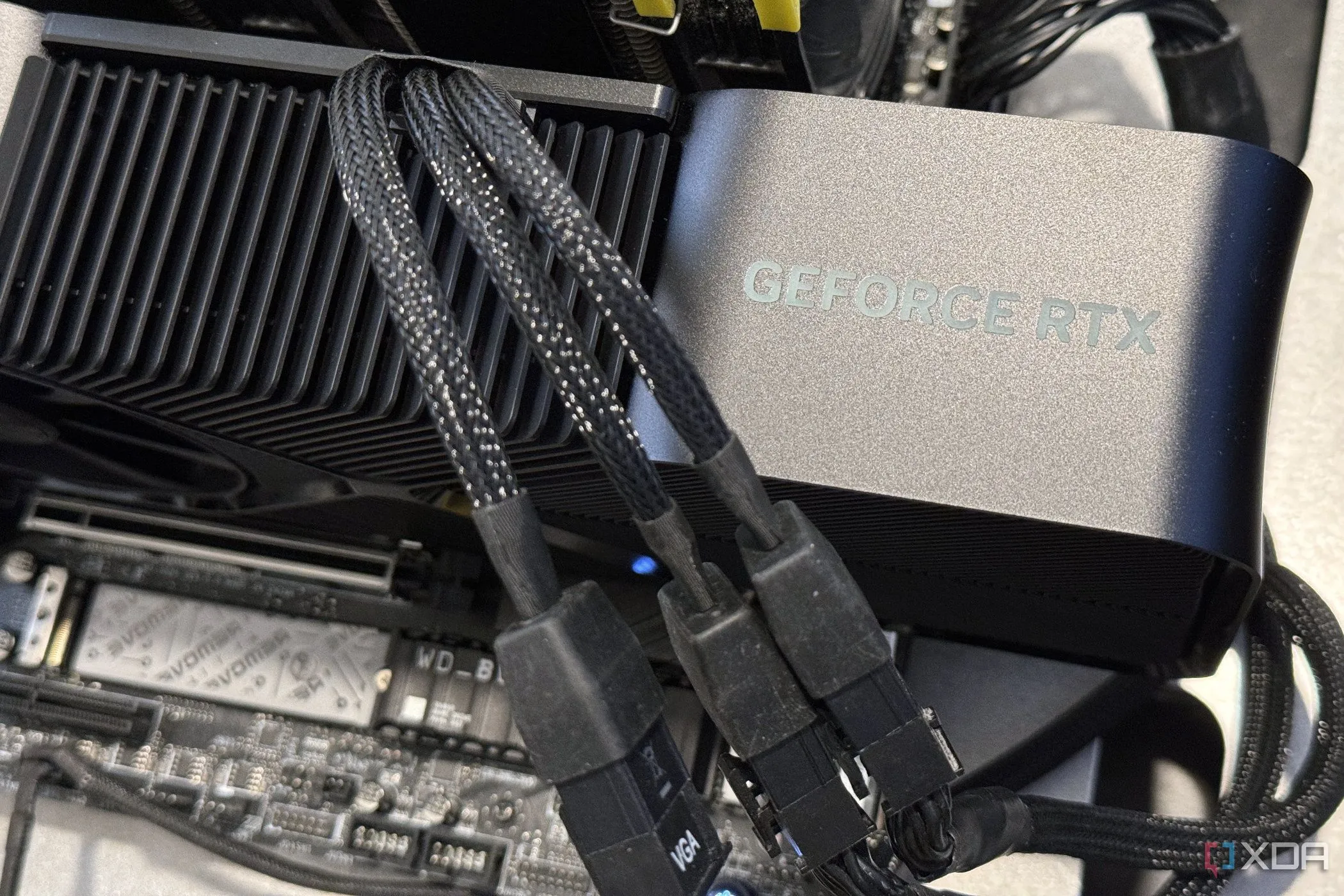 Card đồ họa Nvidia GeForce RTX 4080 Super Founders Edition được lắp đặt, hiển thị ba cáp nguồn kết nối vào bộ chuyển đổi, minh họa cho yêu cầu cấp điện của GPU.