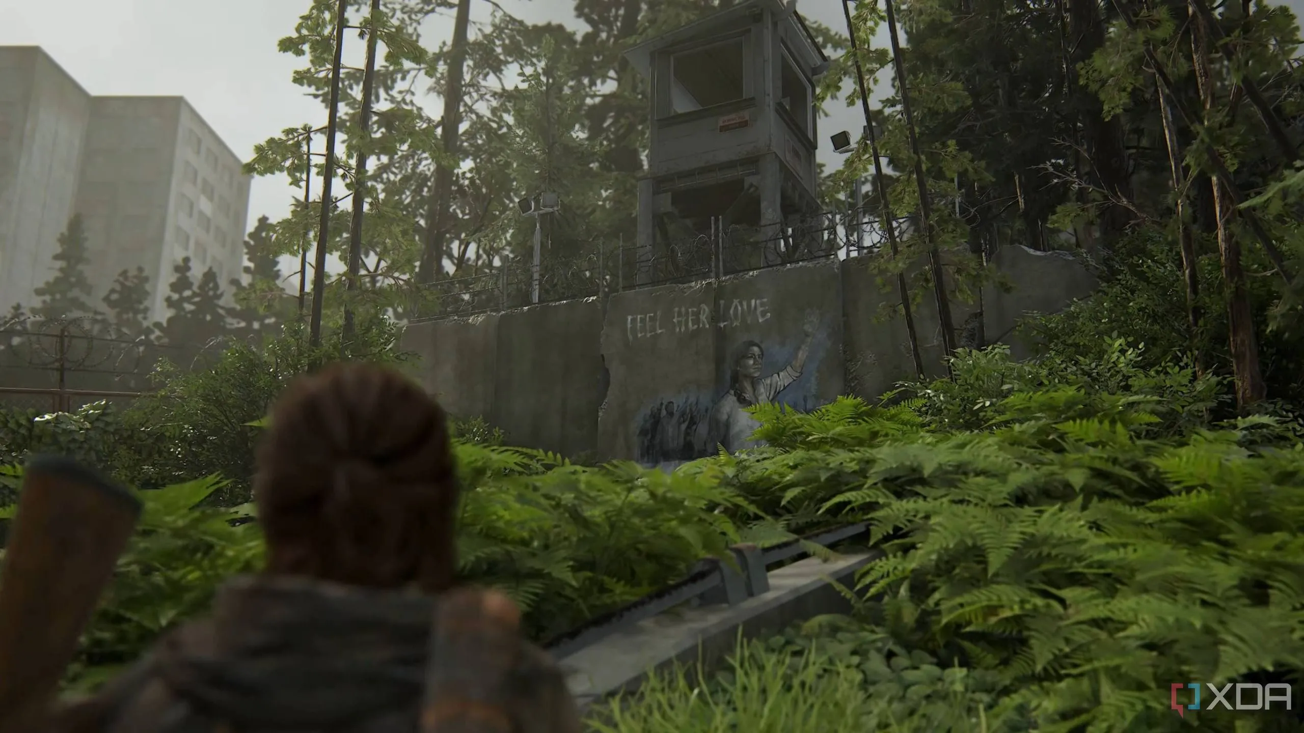 Ellie quan sát bức tranh tường của phe Scars trong game The Last of Us Part II Remastered