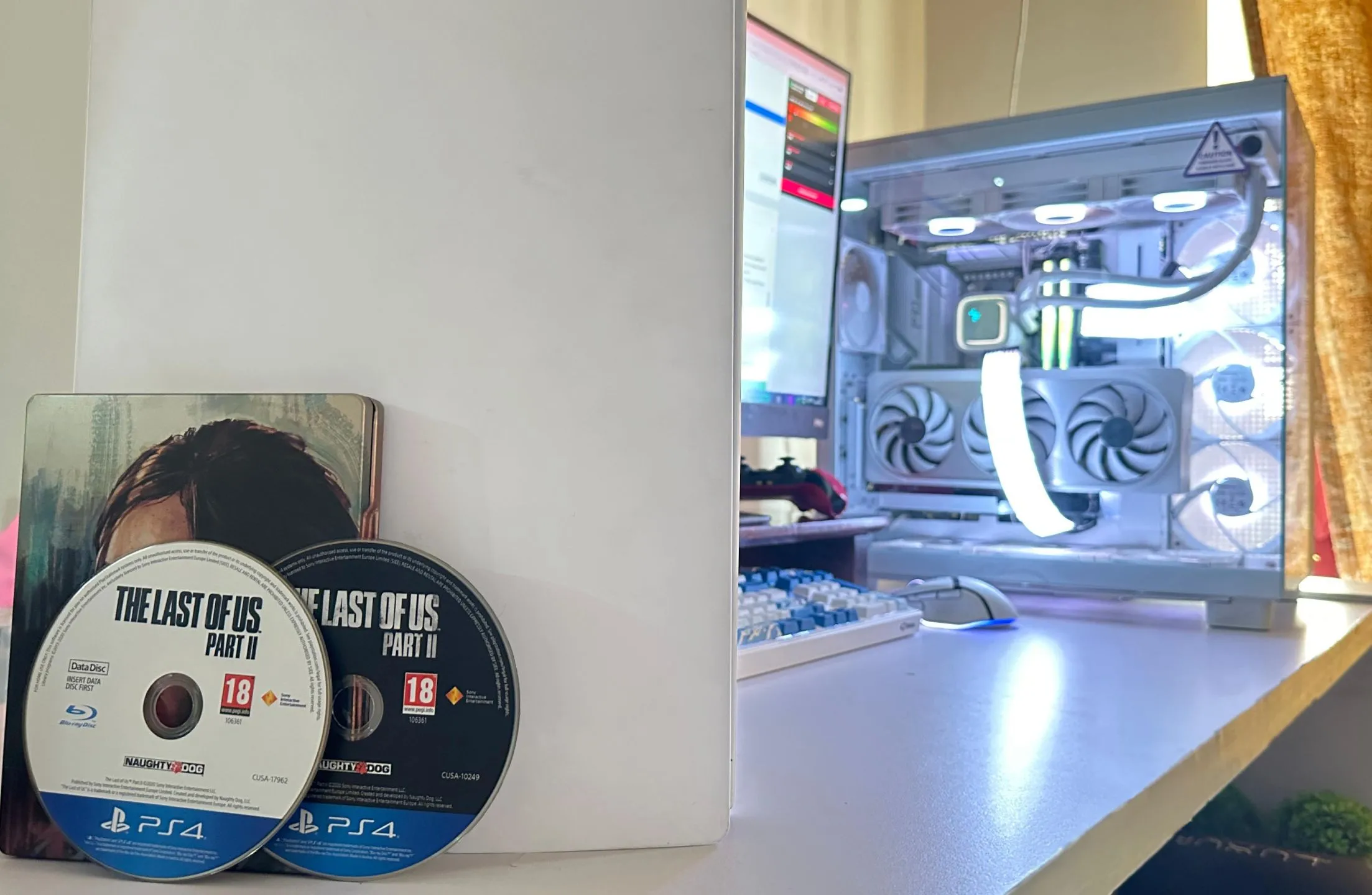 Hai đĩa game The Last of Us Part II phiên bản PS4 đặt cạnh PC và PS5, cho thấy kích thước game lớn cần nhiều phương tiện vật lý.