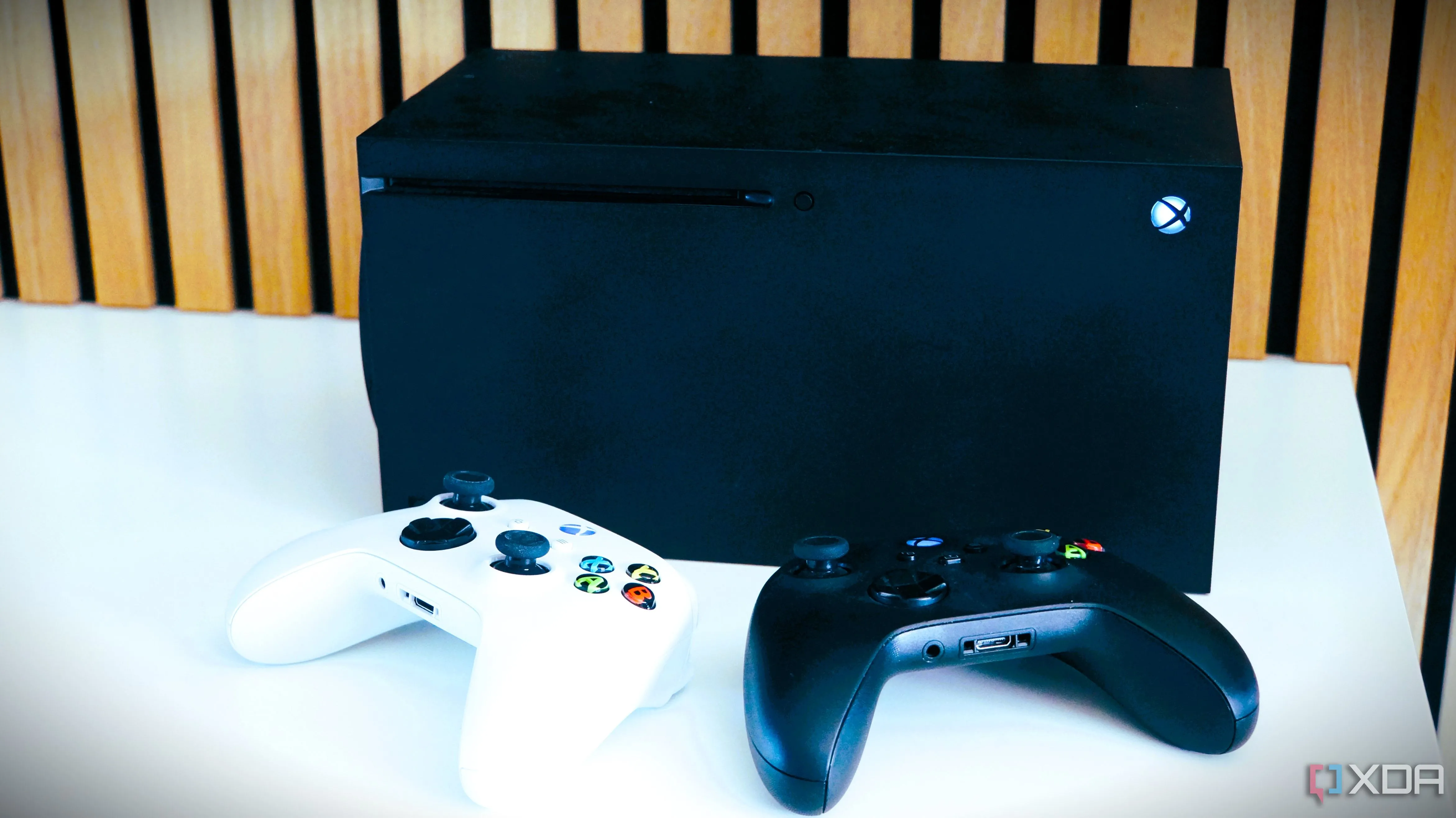 Hai tay cầm Xbox đặt trước máy chơi game Xbox Series X, thể hiện các sản phẩm phần cứng game chịu ảnh hưởng tăng giá