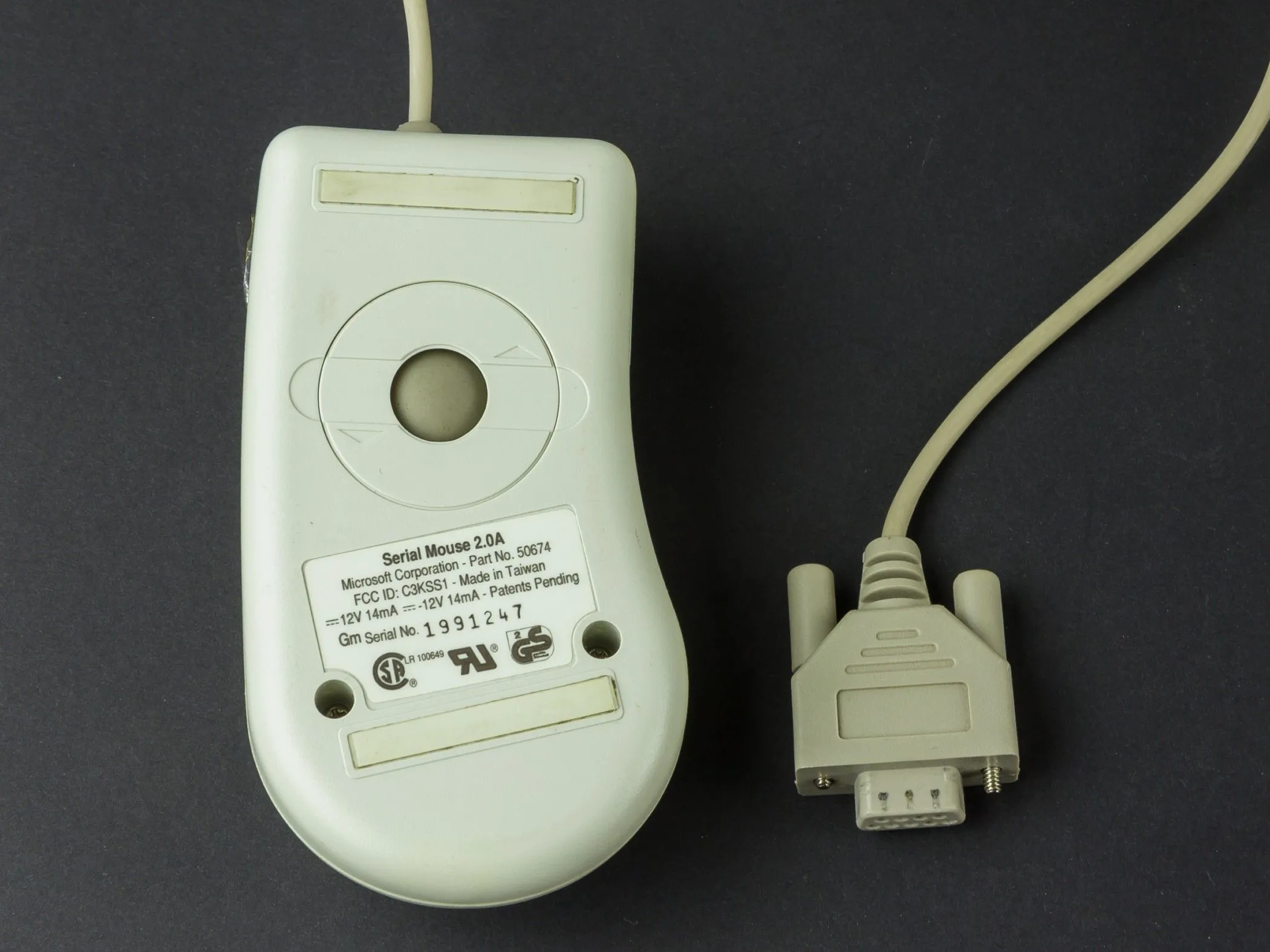 Hình ảnh một con chuột máy tính sử dụng cổng Serial hoặc PS/2, với bi lăn đặc trưng, minh họa cho chuột bi lỗi thời.