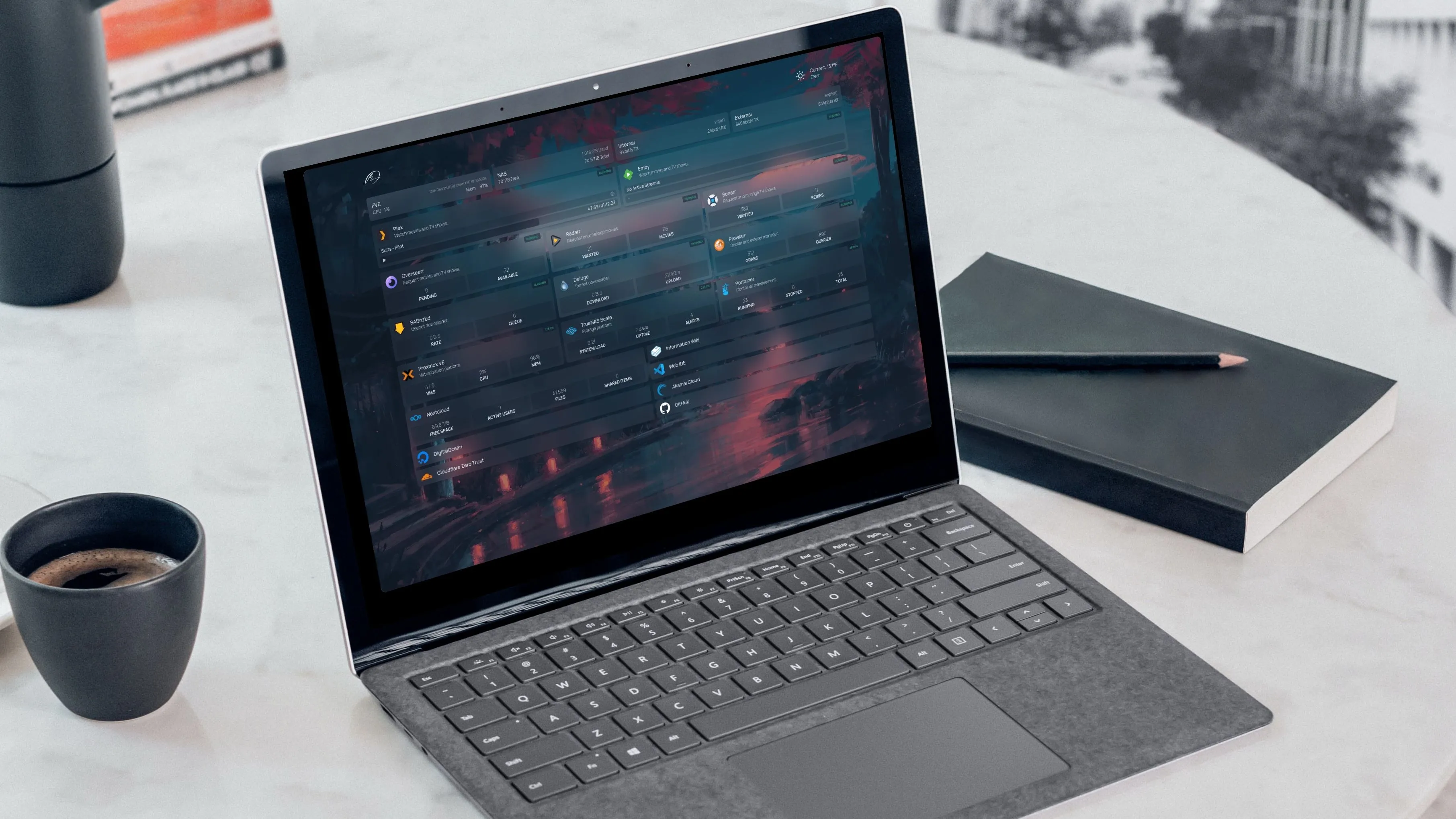 Laptop với bảng điều khiển tự host Homarr trên màn hình, cạnh cốc cà phê và sổ tay.