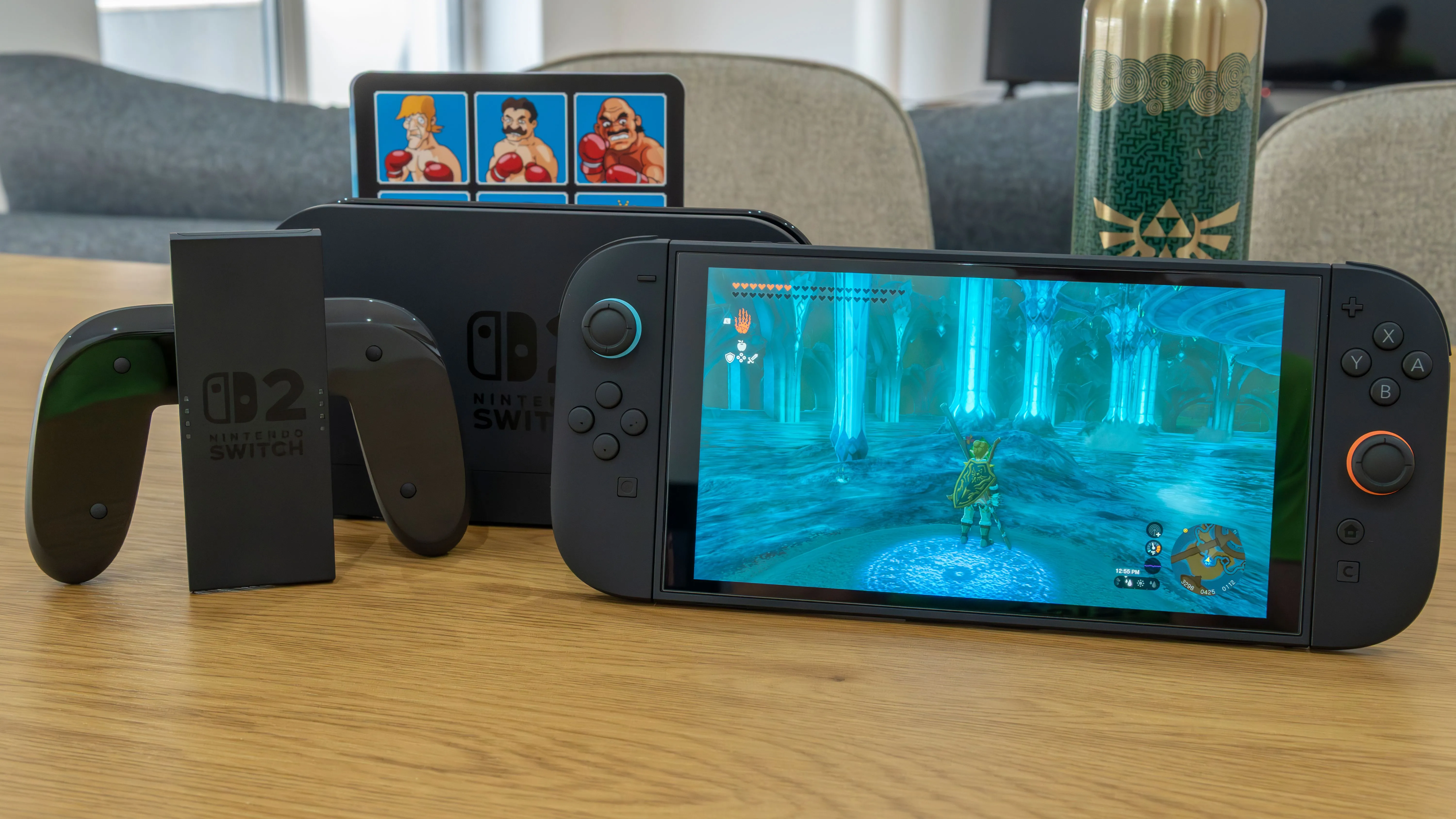 Máy chơi game Nintendo Switch 2 cùng dock và tay cầm Joy-Con 2 trên bàn gỗ, hiển thị game The Legend of Zelda: Tears of the Kingdom, minh họa sức mạnh của console.
