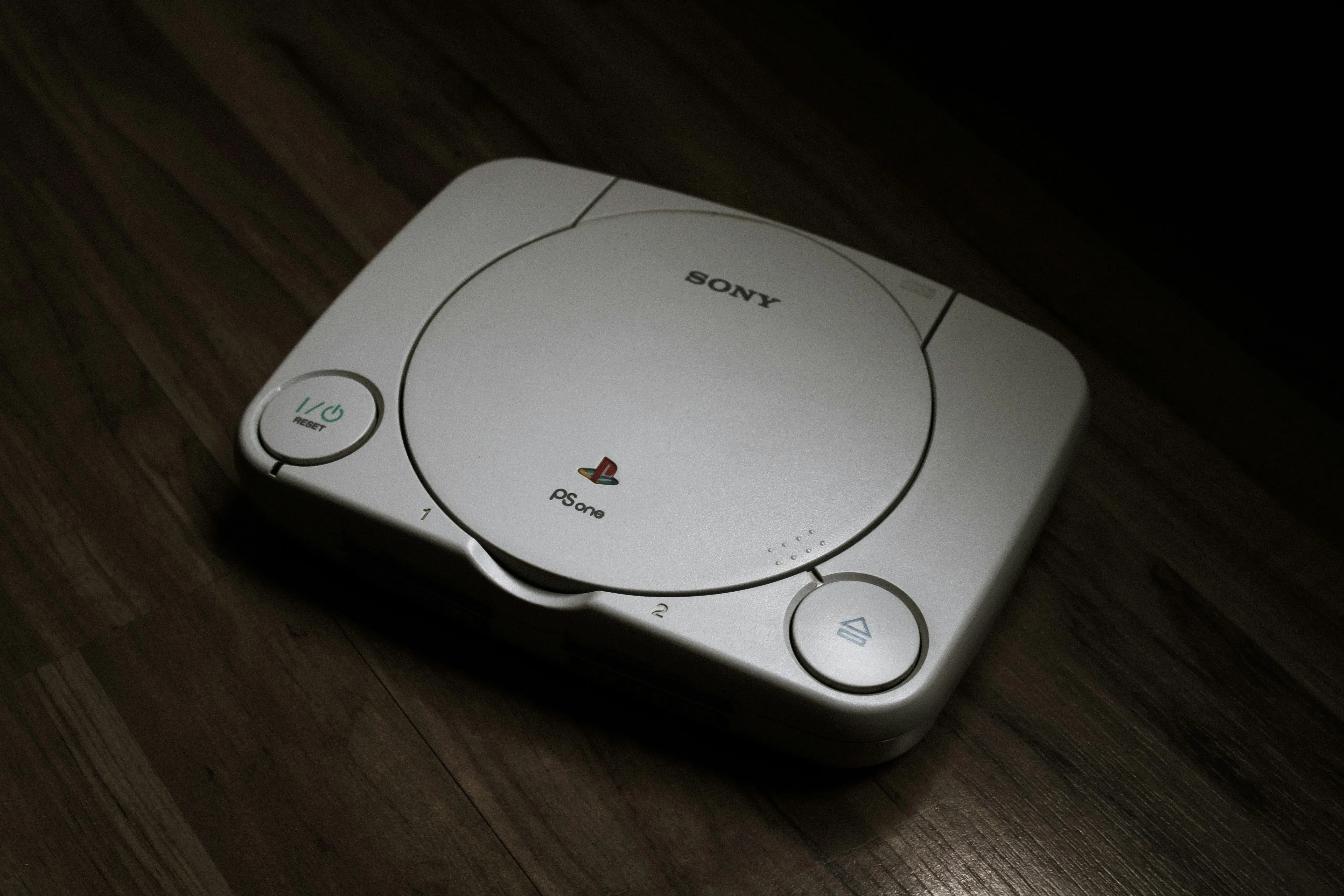 Máy chơi game PlayStation 1 đặt trên sàn gỗ, minh họa cho sự giao thoa kiến trúc với PC