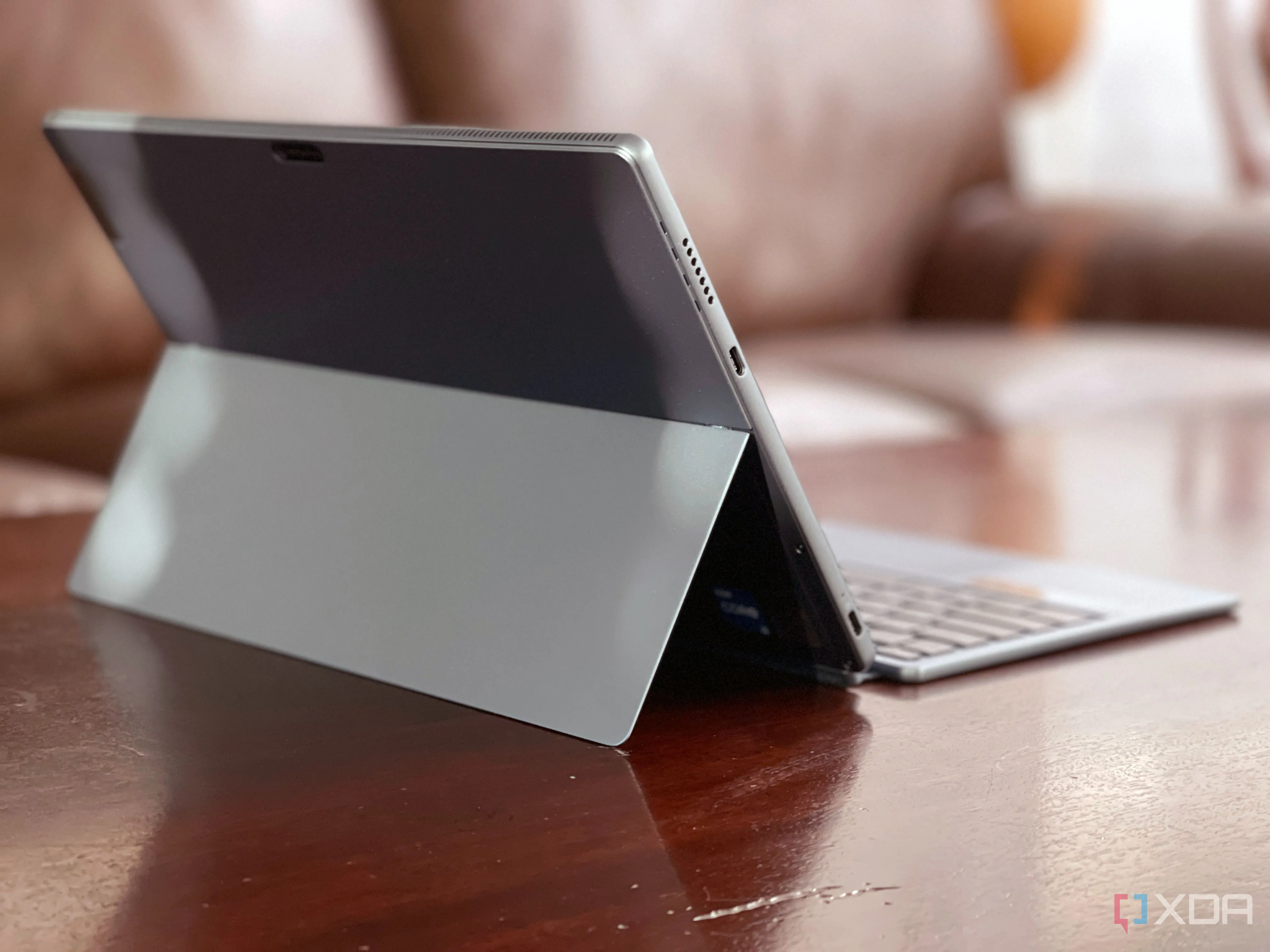 Máy tính bảng Lenovo IdeaPad Duet 5i đặt trên bàn, phía sau là ghế sofa, thể hiện tính linh hoạt và di động