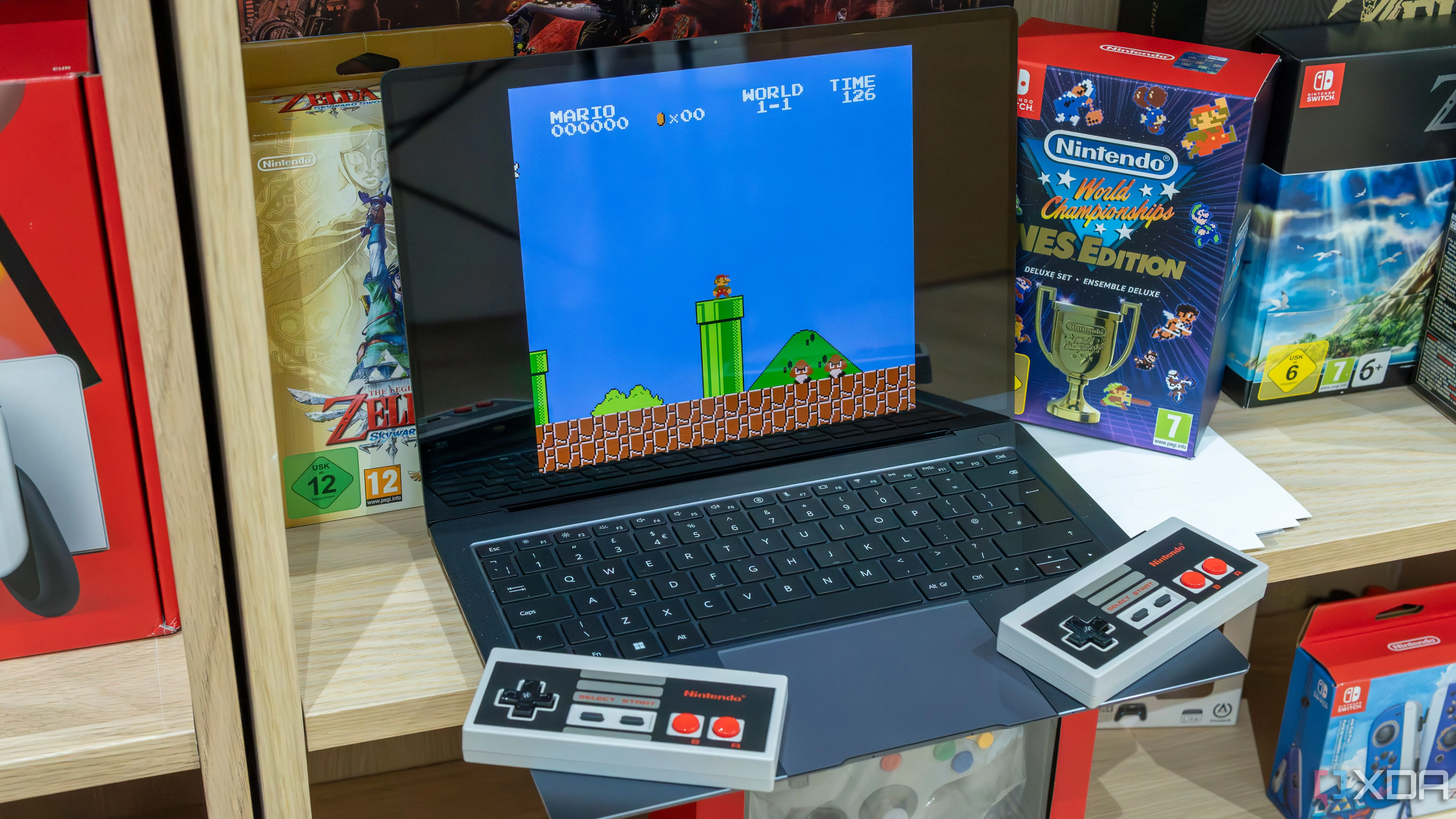 Mô tả: Máy tính xách tay chạy Windows 11 đang giả lập game Super Mario Bros cùng hai tay cầm NES không dây.