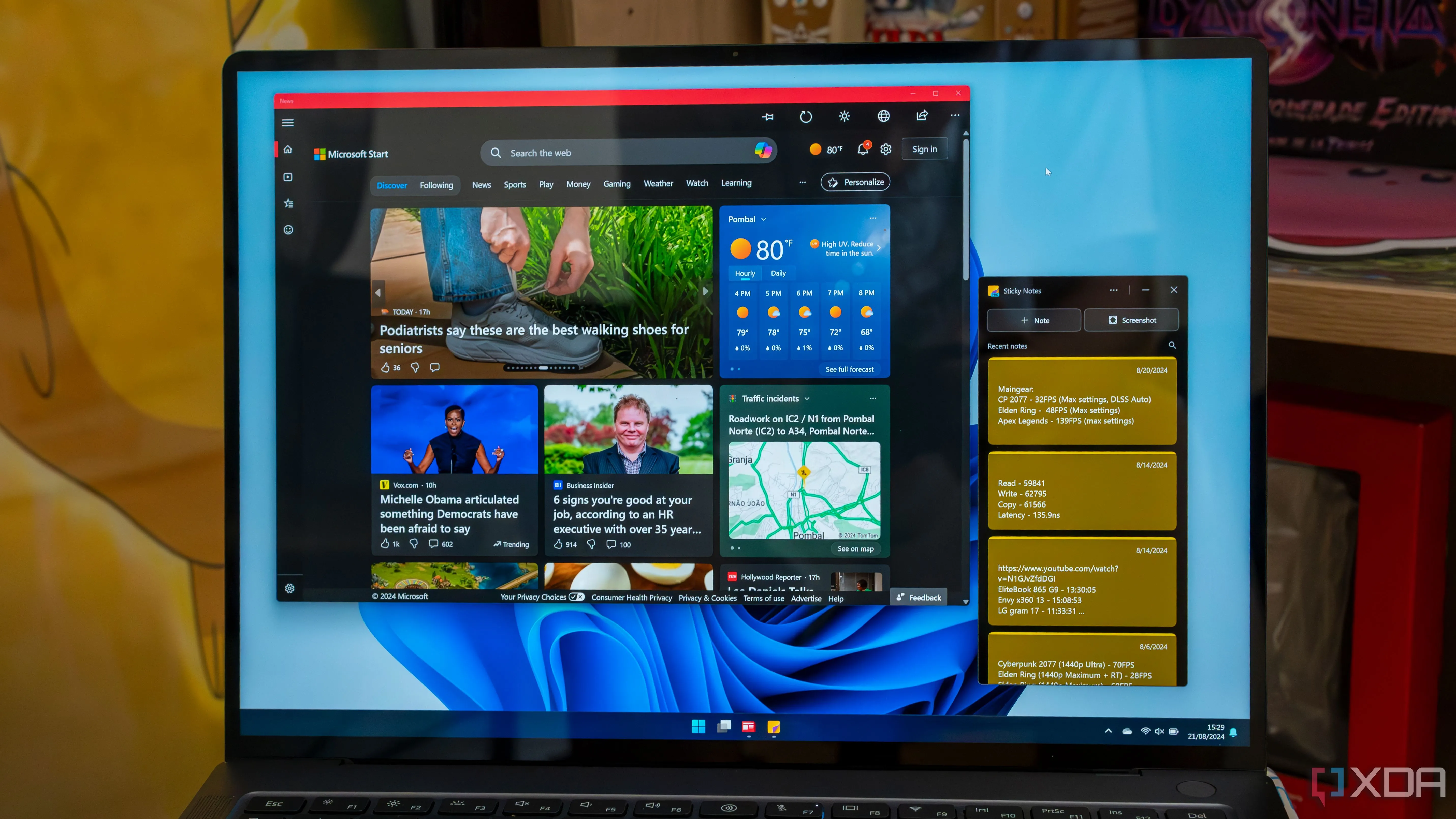 Một chiếc laptop Windows 11 đang chạy ứng dụng Microsoft News và Sticky Notes