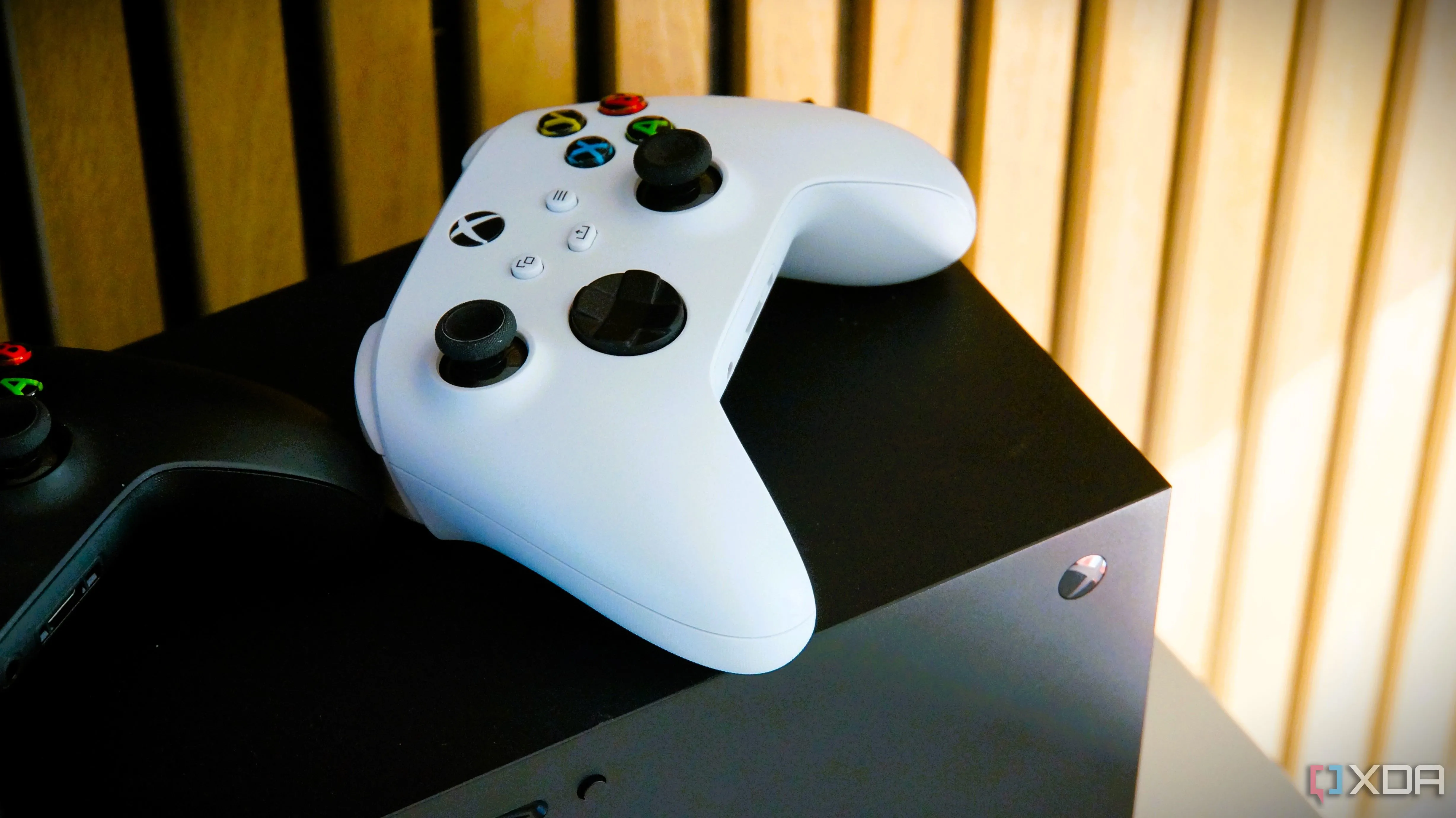 Một chiếc tay cầm Xbox màu trắng đặt trên đỉnh một máy chơi game Xbox Series X.