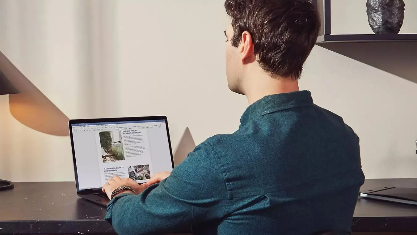 Một người đàn ông đang làm việc với tài liệu trên Microsoft Word, minh họa sự quen thuộc của người dùng với ứng dụng văn phòng này