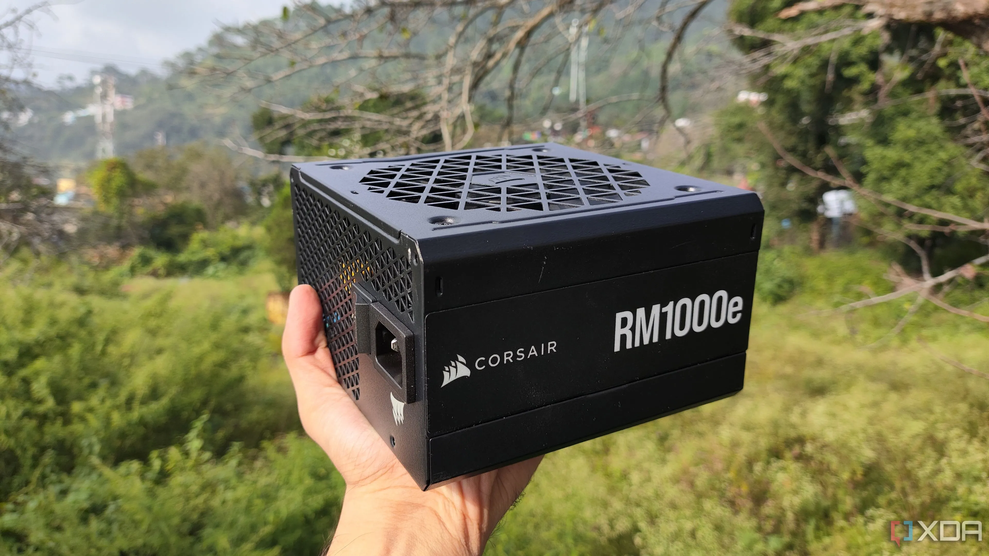 Một người đang cầm bộ nguồn máy tính Corsair RM1000e, minh họa tầm quan trọng của việc lựa chọn PSU chất lượng và nhà sản xuất gốc (OEM) uy tín cho hệ thống PC.