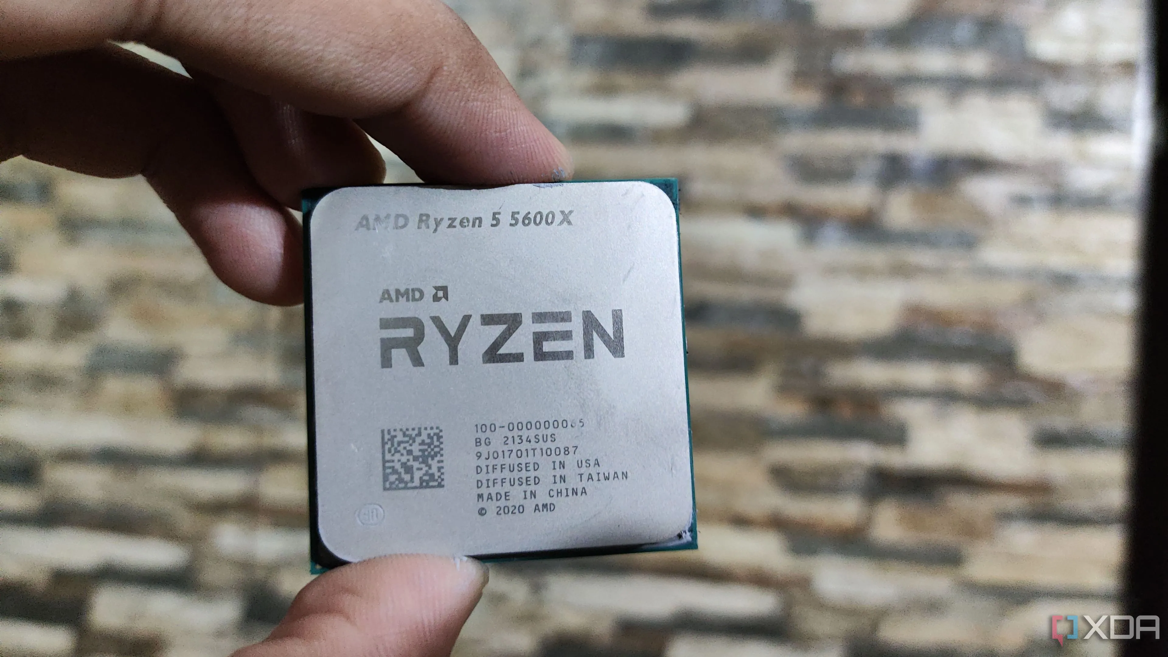 Một người đang cầm bộ vi xử lý AMD Ryzen 5 5600X, tượng trưng cho lựa chọn CPU 6 nhân tối ưu cho gaming thay vì CPU 8 nhân không cần thiết.