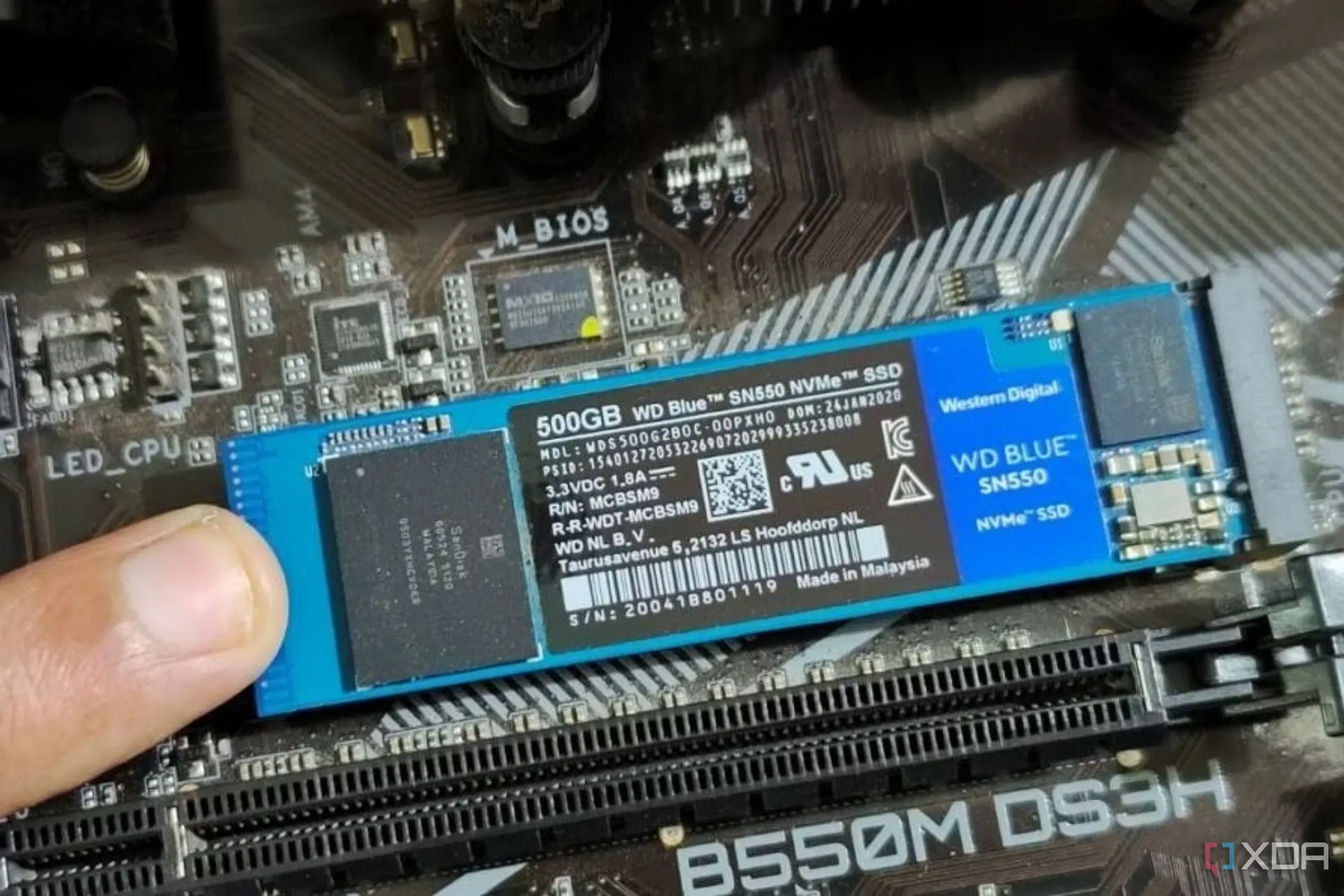 Một người đang cầm và cố định mô-đun SSD M.2 trên bo mạch chủ, minh họa việc nâng cấp lưu trữ cho PC.