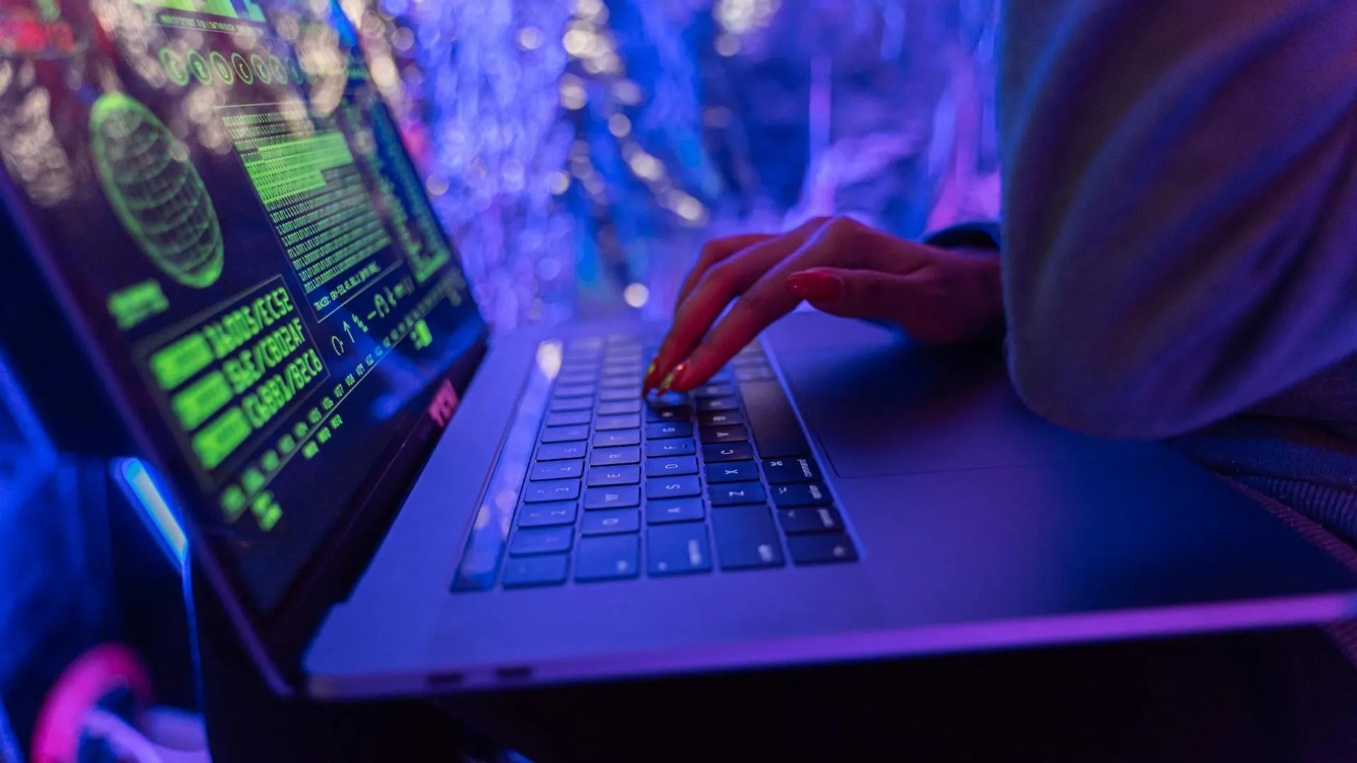 Một người đang sử dụng laptop hiển thị mã code, liên quan đến nguy cơ ransomware mã hóa dữ liệu và đòi tiền chuộc.