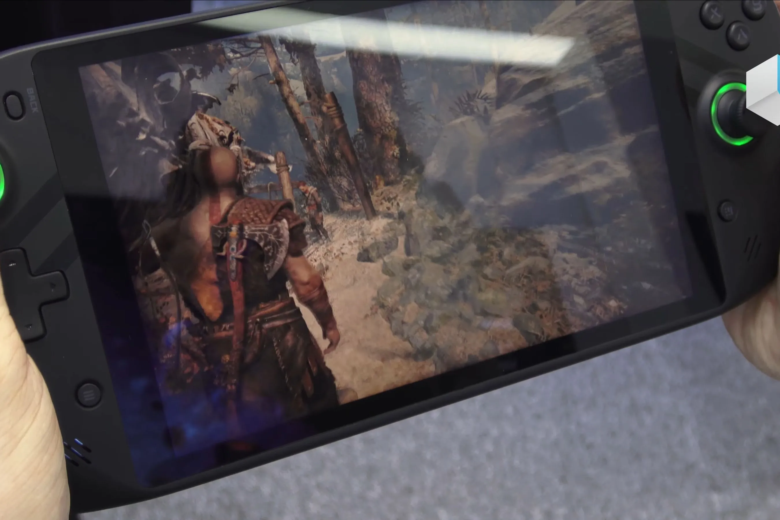Một thiết bị PC gaming handheld đang hiển thị cảnh chơi game God of War, cho thấy trải nghiệm di động của Kratos