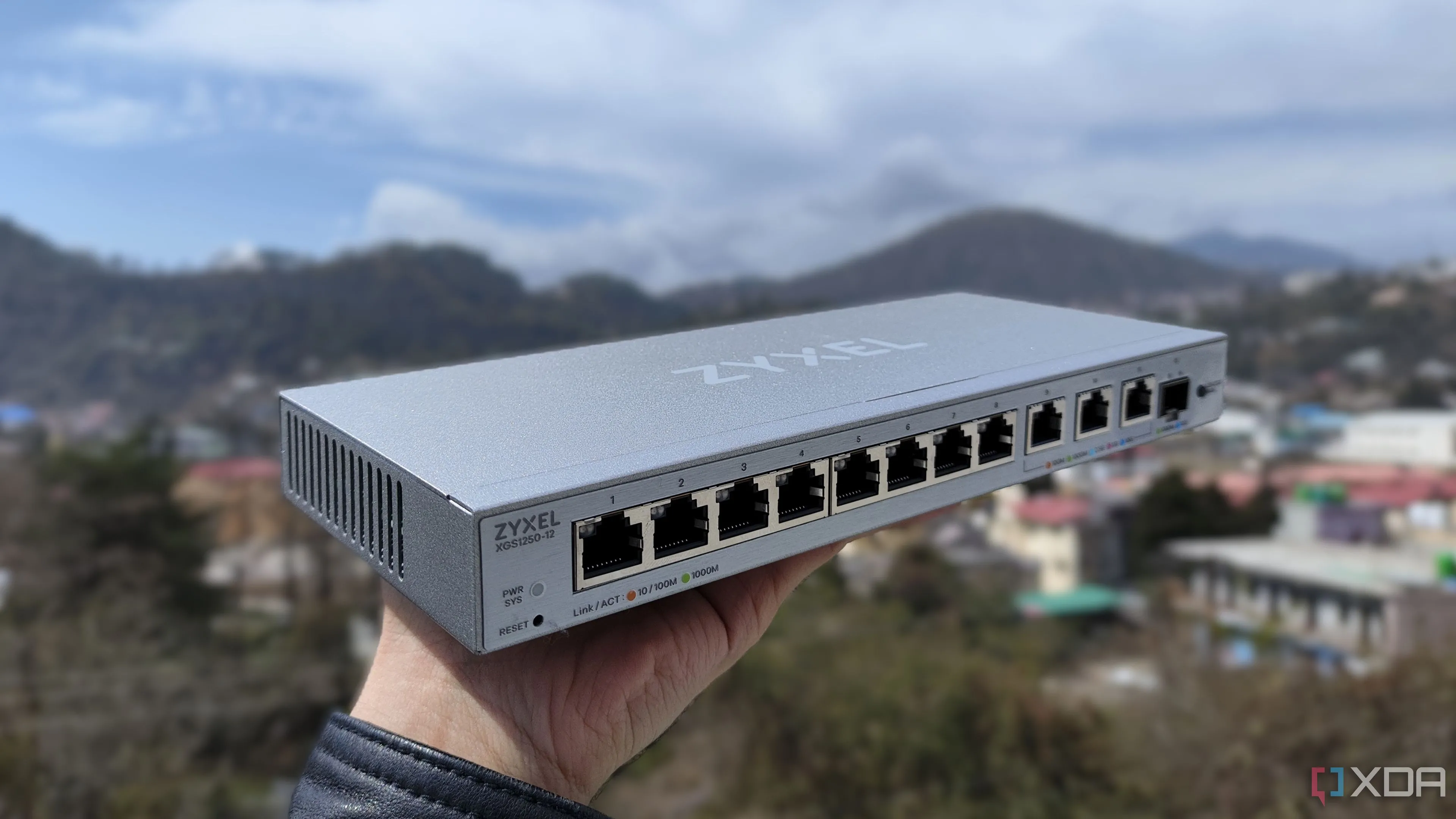 Người đang cầm một bộ chia mạng Zyxel, thiết bị cần thiết để cấu hình VLANs hiệu quả