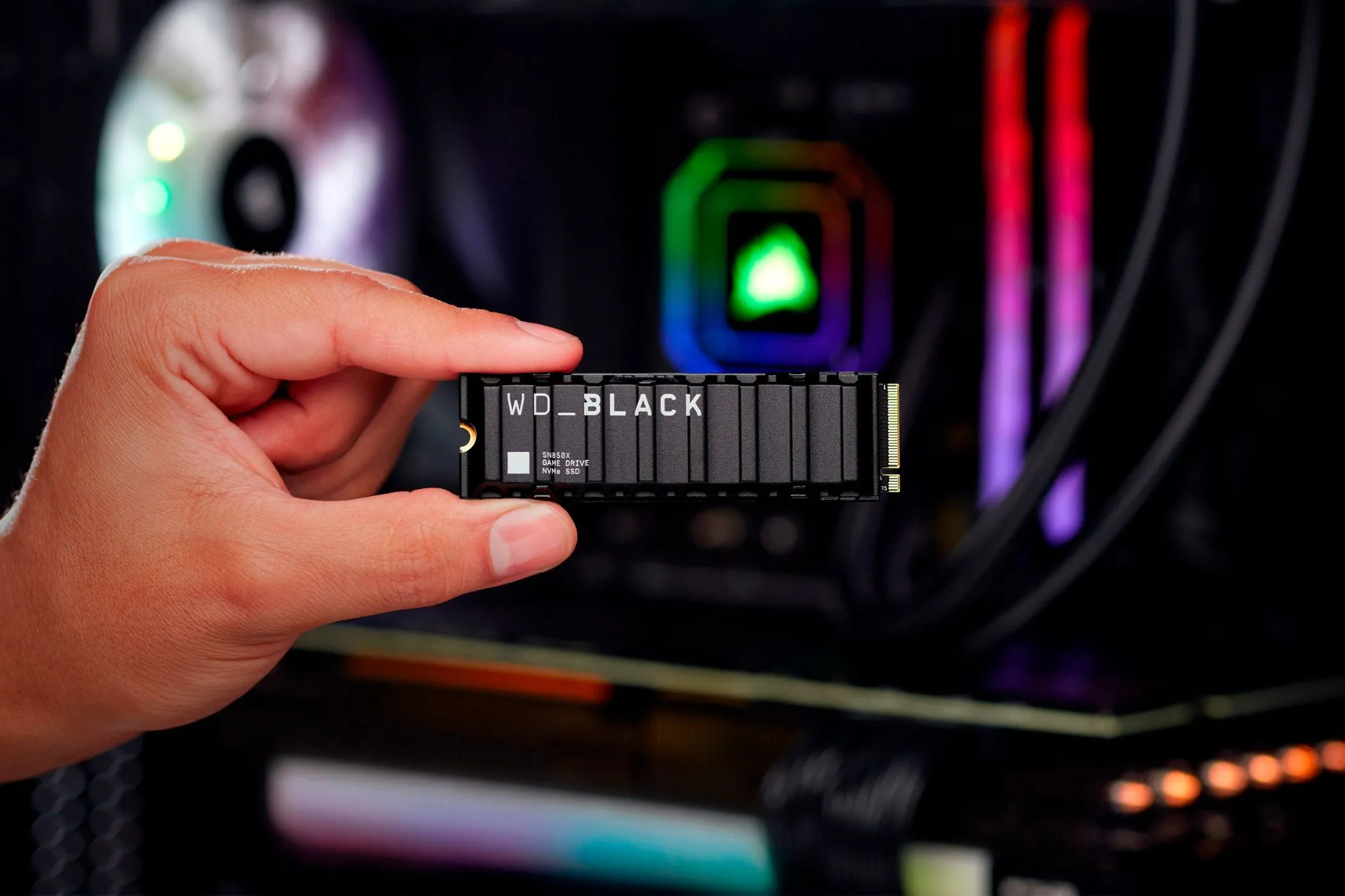 Người dùng cầm SSD WD Black SN850X hiệu năng cao trước dàn PC gaming RGB lung linh