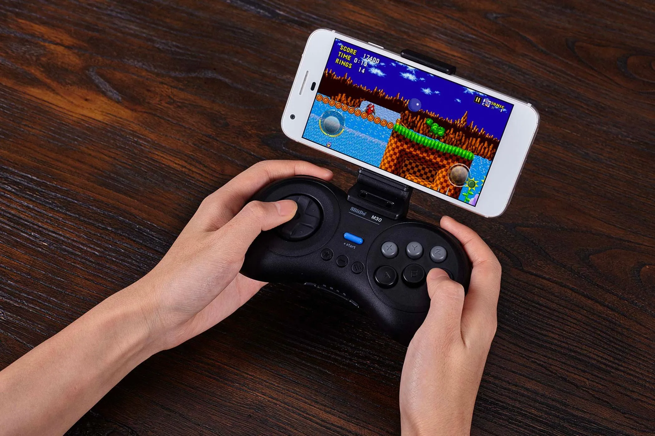 Người dùng chơi game retro trên điện thoại với tay cầm 8Bitdo M30, thể hiện xu hướng hoài niệm trong game hiện đại.
