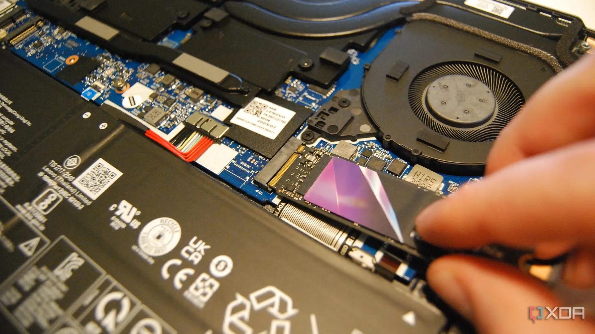 Người dùng đang lắp đặt ổ cứng SSD M.2 NVMe vào khe cắm trên bo mạch chủ laptop để nâng cấp dung lượng và tốc độ