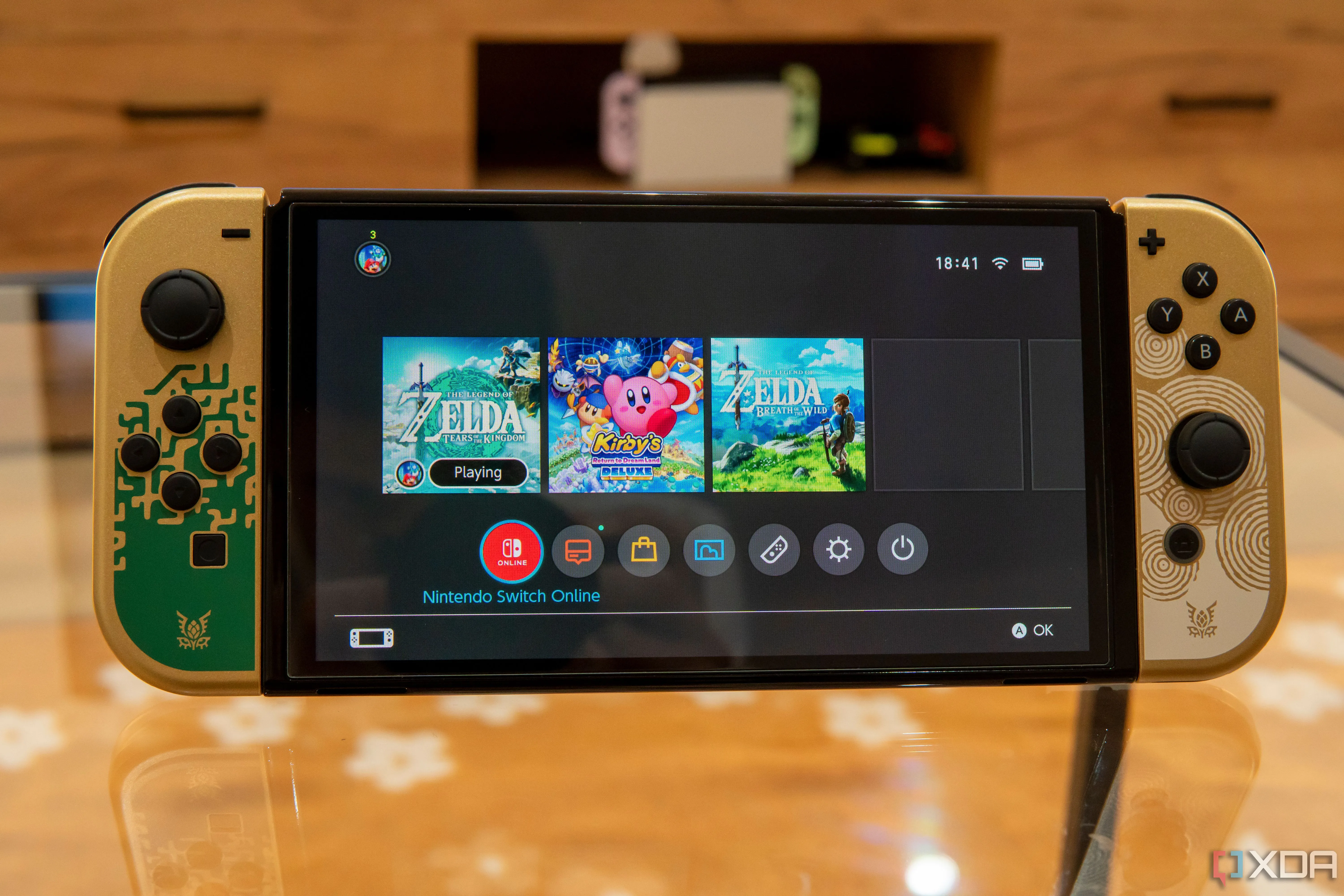Nintendo Switch OLED hiển thị menu chính với game đang chạy nền
