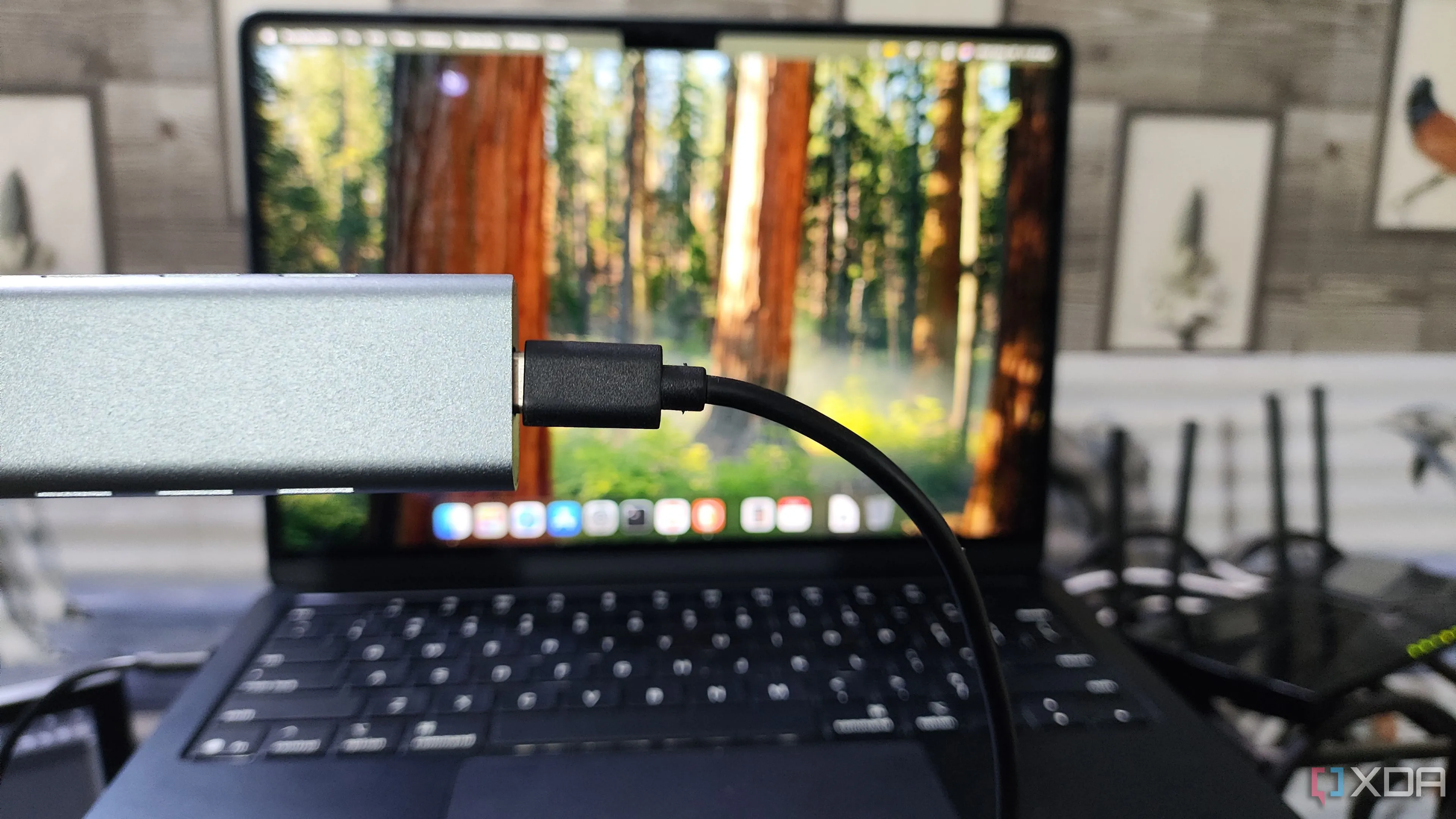 Vỏ bọc NVMe SSD được cầm trước MacBook, biến SSD cũ thành ổ đĩa di động tốc độ cao